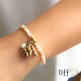 Pulseira em banho ouro 18k cristais perolado com pingentes pérola água doce, trevo 4 folhas e figa